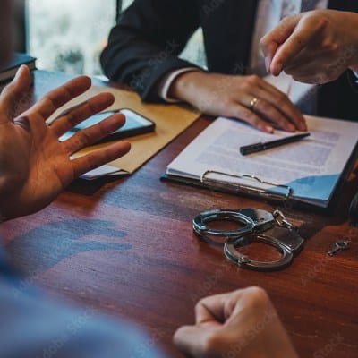 Attorney reviewing documents with a client in handcuffs
